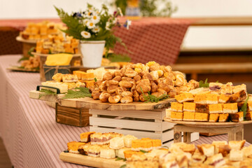 Assorted baked goods displayed on wooden tables with flowers in a rustic setting