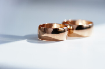 Two rose gold wedding bands rest on a clean surface, their polished surfaces catching soft light. Subtle shadows and reflections convey romance, elegance, and lasting commitment