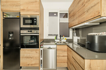 Detail of the sink area in a small kitchen, showing an undermount stainless steel sink and a front-loading dishwasher with an integrated front