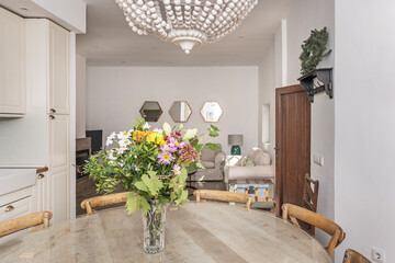 Dining set with a round recycled teak table and beach chairs, with a bouquet of hibiscus and tropical bougainvillea