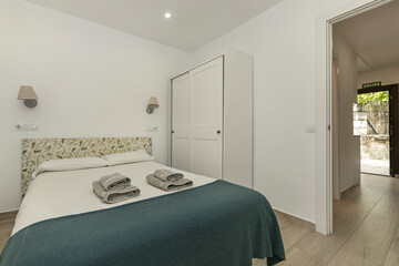 Photograph of a hotel bedroom with a king-size bed and a heavyweight white sheet, professionally folded to standard specifications