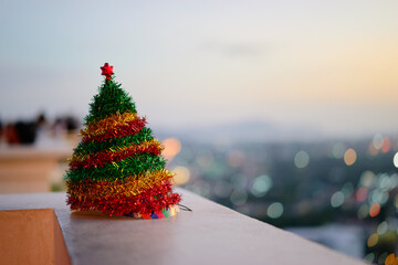 Obraz premium Festive Mini Christmas Tree Decorated With Colorful Tinsel On Balcony