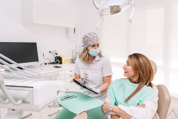 Female Dentist explaining treatment to patient using tablet in modern dental clinic