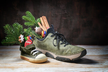 Small and large sneaker filled with treats on Nicholas or Nikolaus day at 6th December, holiday...