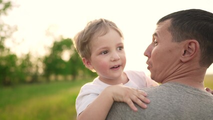 son hugging dad in the park. happy family a father day kid dream concept. baby baby boy walking with dad in nature lifestyle in his arms. baby hugging dad in the park