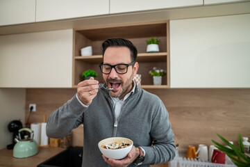 Man eating healthy breakfast cereal in kitchen