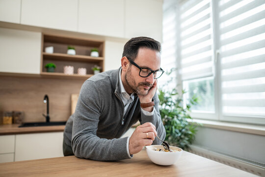 Man contemplating while eating breakfast cereal in kitchen