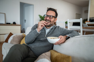 Man relaxing on couch eating snack and laughing