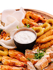 Seafood platter with shrimp, fish and dips served on a wooden tray