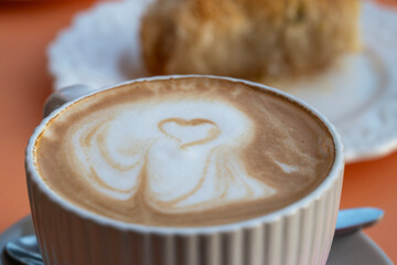 A white ceramic cup of cappuccino with heart-shaped latte art