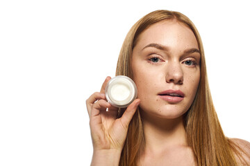Stunning young woman showcasing skincare product with a captivating expression