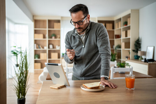 Man online shopping with credit card holding tablet at home - Powered by Adobe