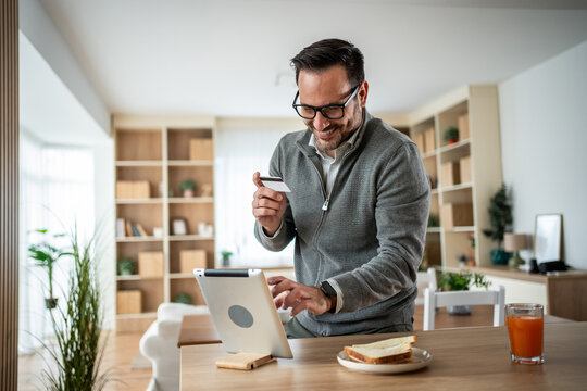 Happy man shopping online with credit card on tablet