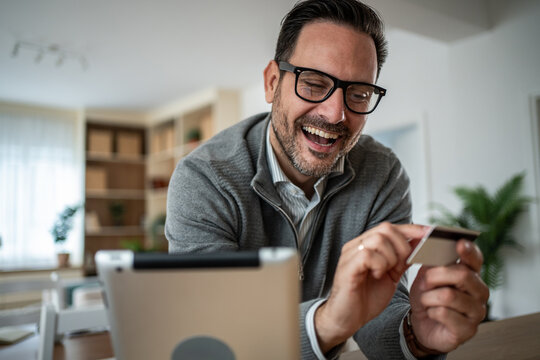 Happy man shopping online with credit card on tablet