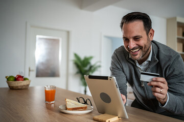 Man shopping online using tablet and credit card at home
