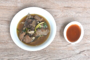 boiled braised beef meat and tendon couple organ in herb brown soup on bowl dipping spicy chili sauce 