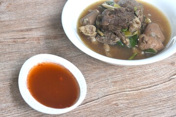 boiled braised beef meat and tendon couple organ in herb brown soup on bowl dipping spicy chili sauce 