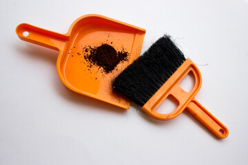 An orange plastic hand broom and dustpan on white background, top view. A compact device that is...