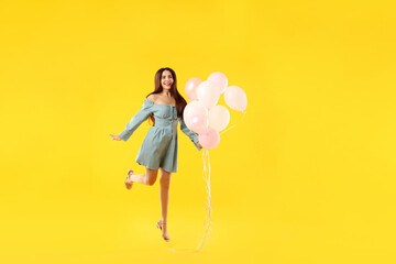 Beautiful woman with balloons jumping on orange background