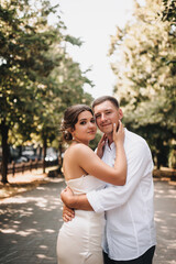 Fototapeta premium Wedding photography, portrait of happy smiling newlyweds, loving couple, fashionable groom and beautiful cute brunette bride, hugging outdoors on the street in the city, in the park.