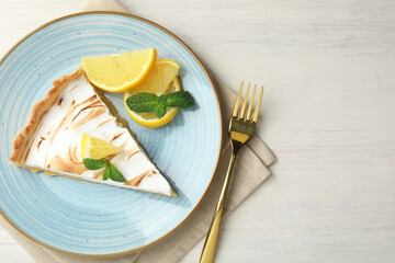 Slice of tasty lemon meringue tart served on white wooden table, flat lay. Space for text