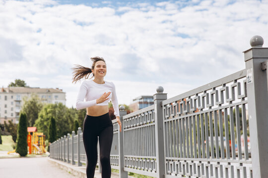 Athletic woman running in park enjoying fitness lifestyle - Powered by Adobe