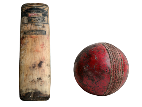 Worn cricket bat stands next to a weathered red leather cricket ball