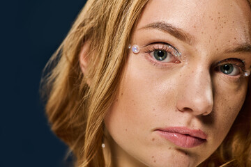 Captivating young woman adorned with unique gems, exuding charm and confidence in a studio setting