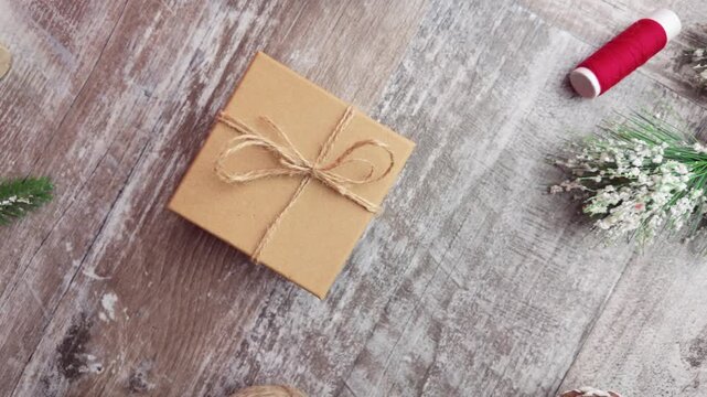 Slow motion overhead shot moving to the right across a rustic wooden table with a wrapped gift and subtle festive flat lay elements