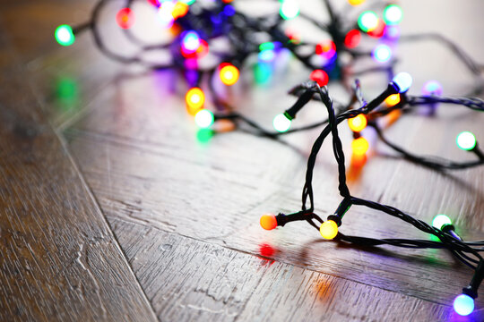 Bright Christmas lights on wooden table, closeup. Space for text