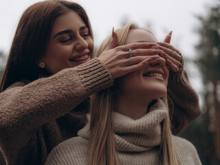 Happy lesbian couple laughing woman playing and covering partners eyes