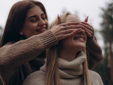 Happy lesbian couple laughing woman playing and covering partners eyes