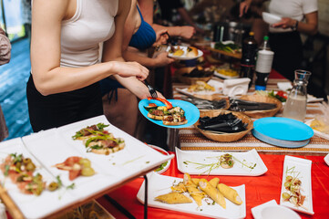 A photograph of people pouring food into dishes in an all-inclusive hotel kitchen. Concept for catering, buffet.