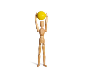 A wooden mannequin toy holding a yellow ball over its head on a white background with copy space