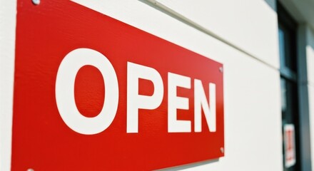 Bright red "OPEN" sign on a white wall, affixed with shiny bolts