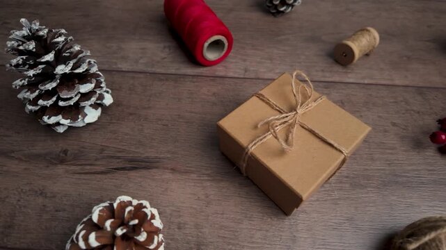 Slow motion slide right capturing gift box and rustic decorations on wooden surface in cozy holiday flat lay style