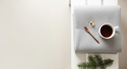 Cozy coffee cup on gray blanket with wooden spoon and pine branch  