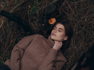 Beautiful young woman lying on ground with closed eyes and resting in forest