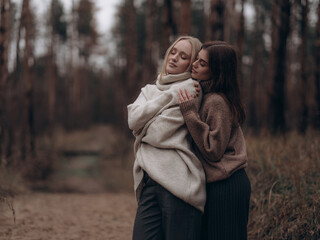 Young lesbian couple embracing side view with closed eyes in forest