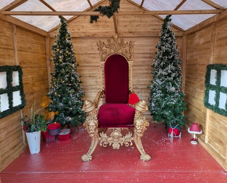 Escenario con caba&ntilde;a con trono dorado de Santa Claus o de los Reyes Magos y &aacute;rboles de navidad para atender las peticiones de los ni&ntilde;os en centro comercial 