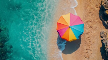 Colorful umbrella resting on sandy beach with clear blue sky and gentle ocean waves