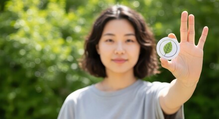 Young woman holding eco-protest badge with leaf symbol in nature  