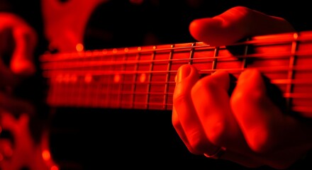 Musician playing an electric guitar under red lighting.