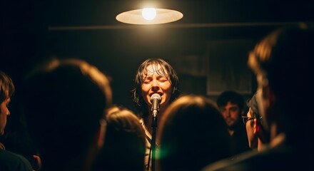 A female singer performs on stage illuminated by a single overhead light.