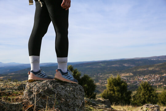 Woman accompanied by her dog wearing Adidas Terrex trail running shoes on a rock in the mountains with a horizon background