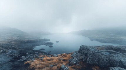 Misty mountain lake scene, serene landscape with foreground rocks, overcast sky, blurred distant horizon