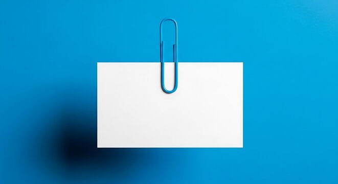 Blue paperclip holding blank white card on blue