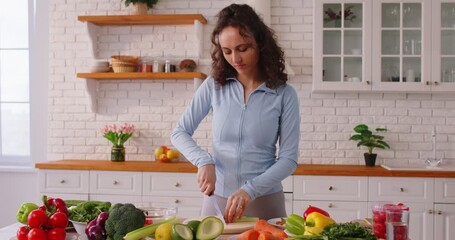 Young woman chopping vegetables bought at market, preparing vegetarian salad on chopping board, standing at kitchen, preparing meal for family supper, keeping to diet, eating healthily - Powered by Adobe