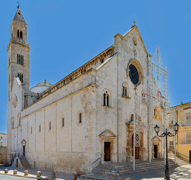 Historic Cathedral of Santa Maria della Porta in Palo del Colle, Apulia, Italy. Romanesque architecture with traditional festival light decorations under a clear blue sky.