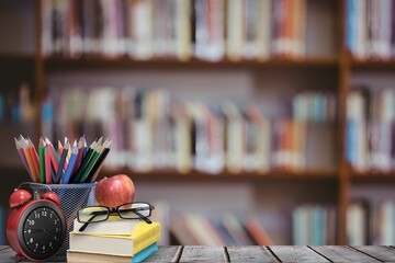 School materials and apple with library background